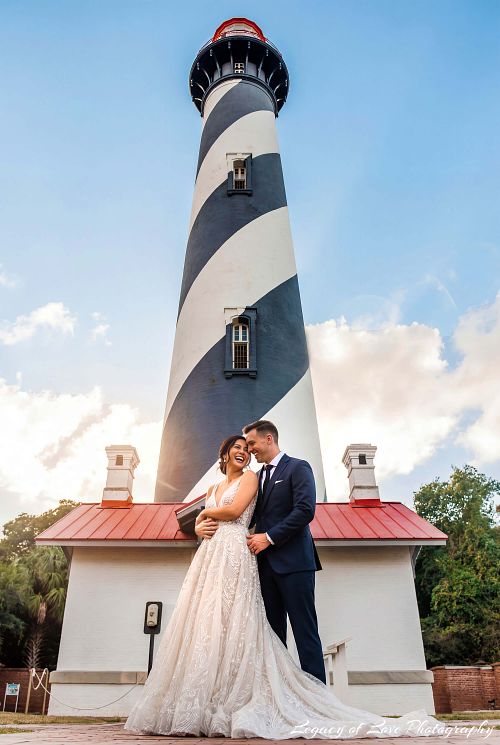 Bride and groom sharing a romantic embrace in front of the St. Augustine Lighthouse, photographed by Legacy of Love Photography.