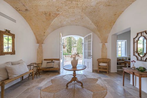 Entrée voûtée en pierre d’une finca d’agrotourisme à Santa Ponça, Minorque, avec table ronde et sol en pierre. Photographie par Nicolas Karadimos.