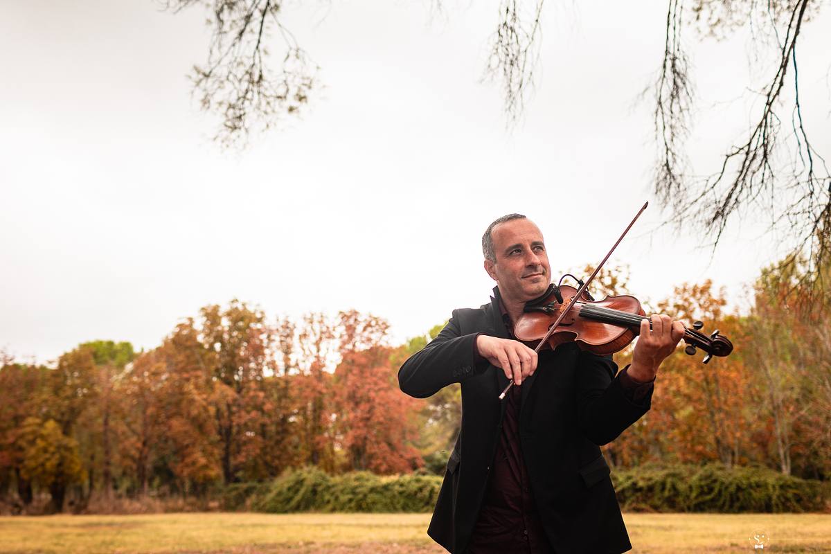 n violoniste habill&eacute; avec &eacute;l&eacute;gance joue de son instrument en plein air, devant un paysage automnal, ajoutant une touche musicale &agrave; l'atmosph&egrave;re du mariage, refl&eacute;tant la joie et la culture qui s'entrem&ecirc;lent &agrave; N&icirc;mes