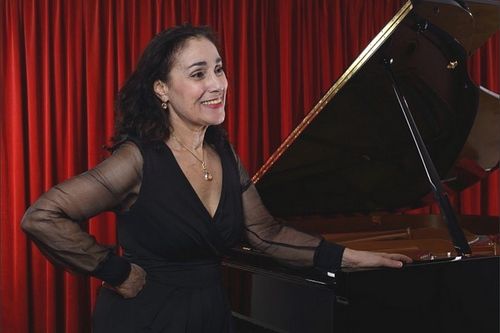 Myriam Birger at the piano before a concert, in front of a red stage curtain