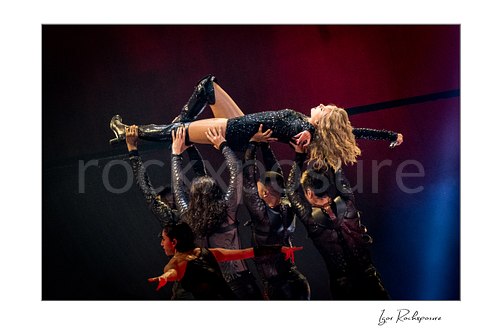 Horizontal color image of Taylor Swift held aloft by dancers on stage in a dramatic performance scene