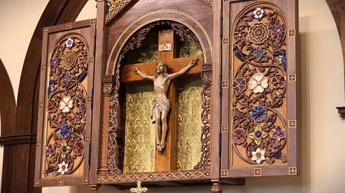 Detail showing the carving, painting, and fabric work on the Crucifix housing.