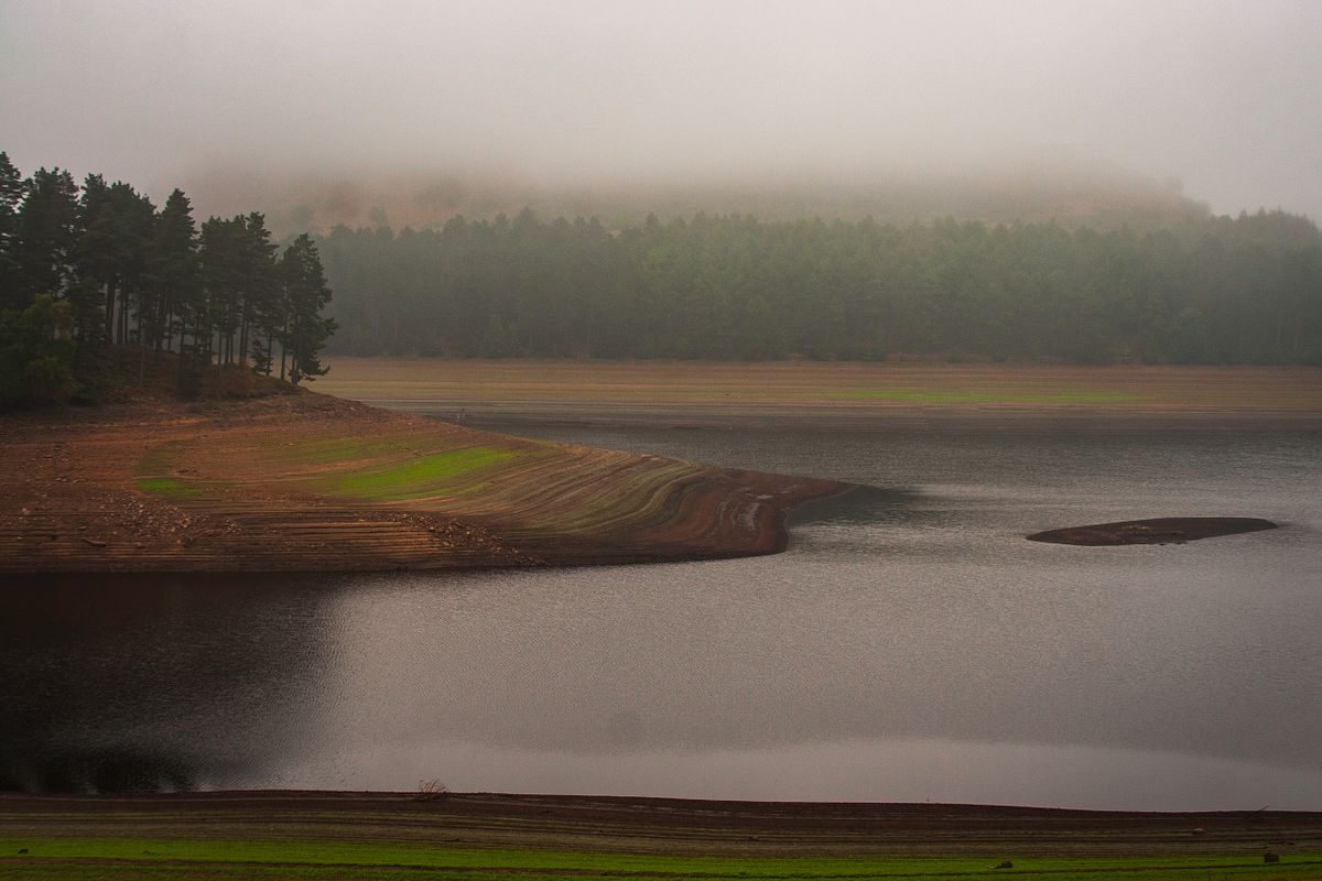 Derwent Water in the Peak District with mist hanging over the trees and hills beyond the water.