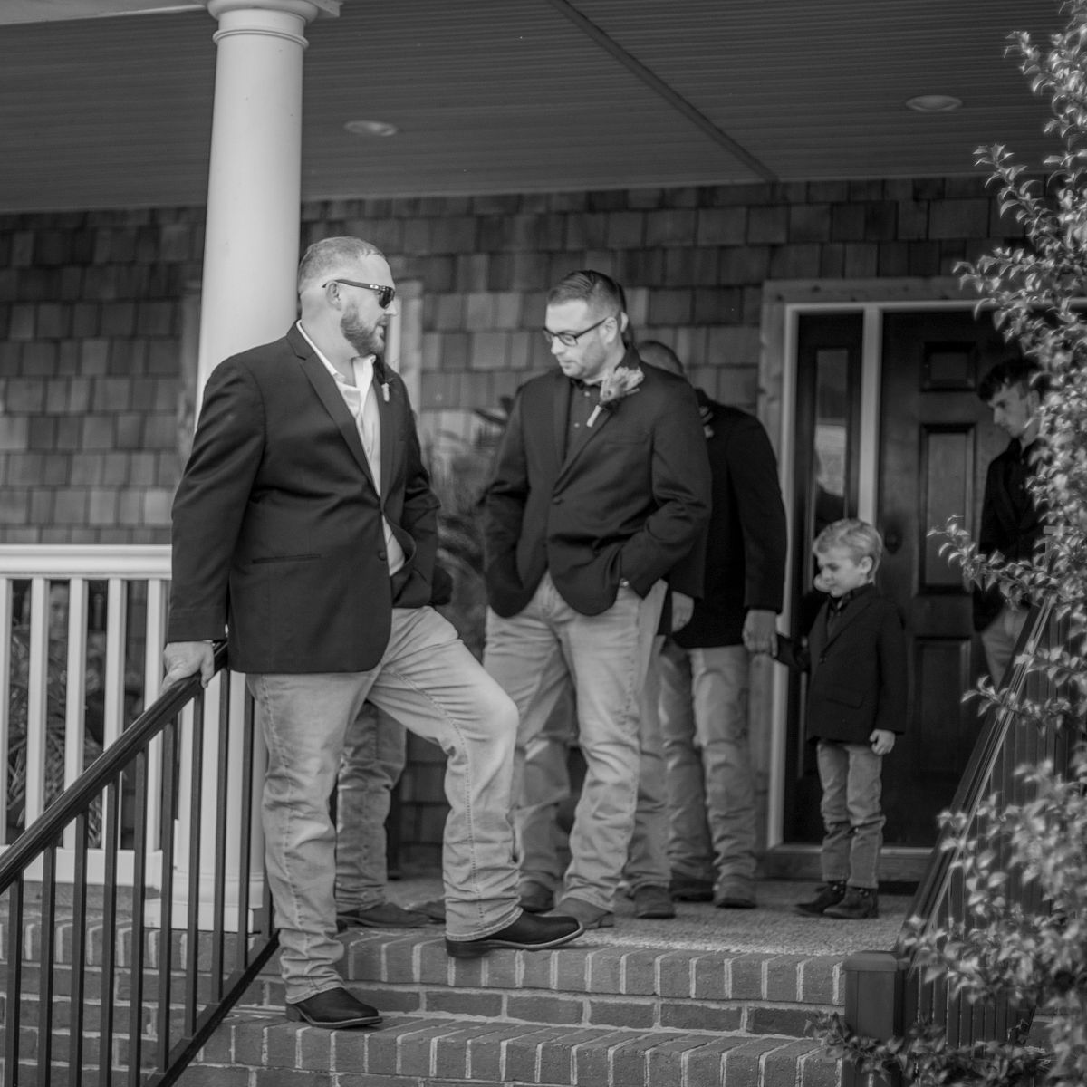 black and white photo of the groom and his groomsmen waiting on the porch at the cohee farm before the ceremony starts