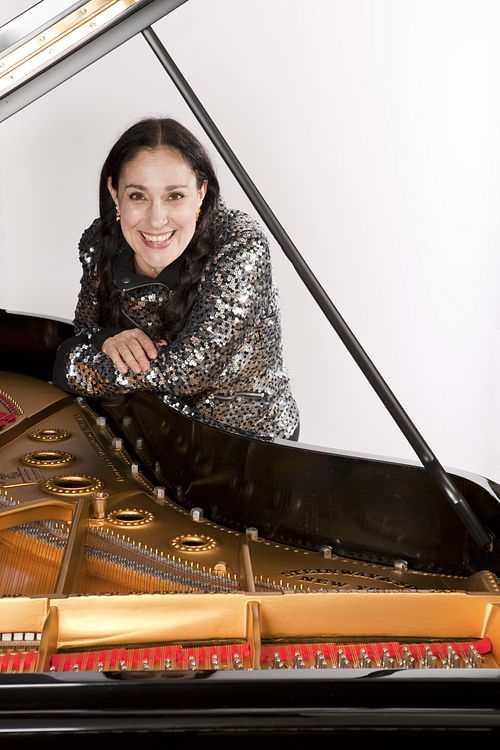 Myriam Birger smiling at the piano during a television appearance, with a view inside the instrument
