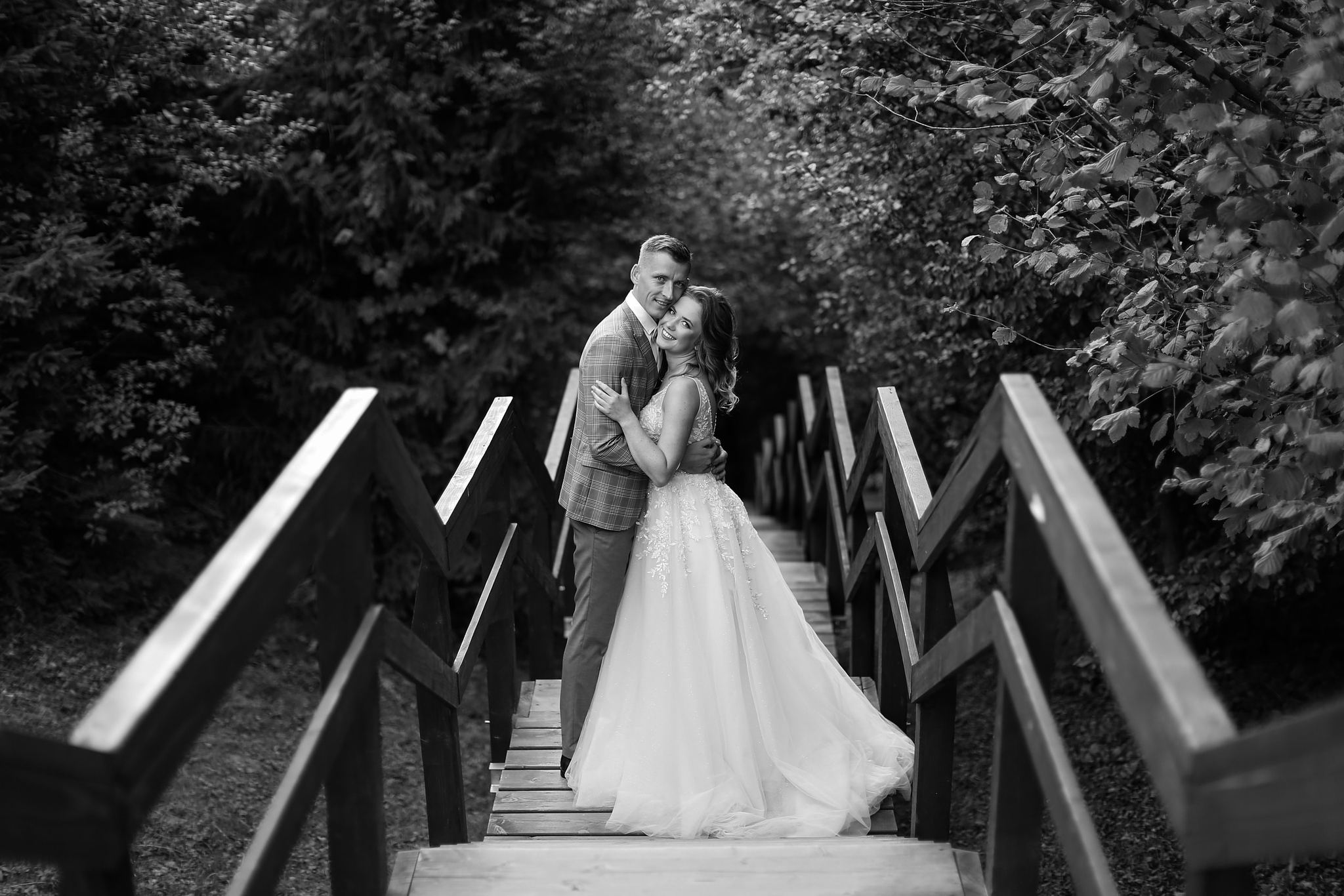 Bride and groom walking across a wooden bridge at Tustan Fortress, Ukraine