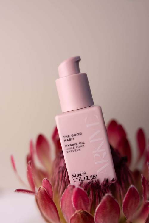Natural skincare bottle styled with pink flowers on a neutral background