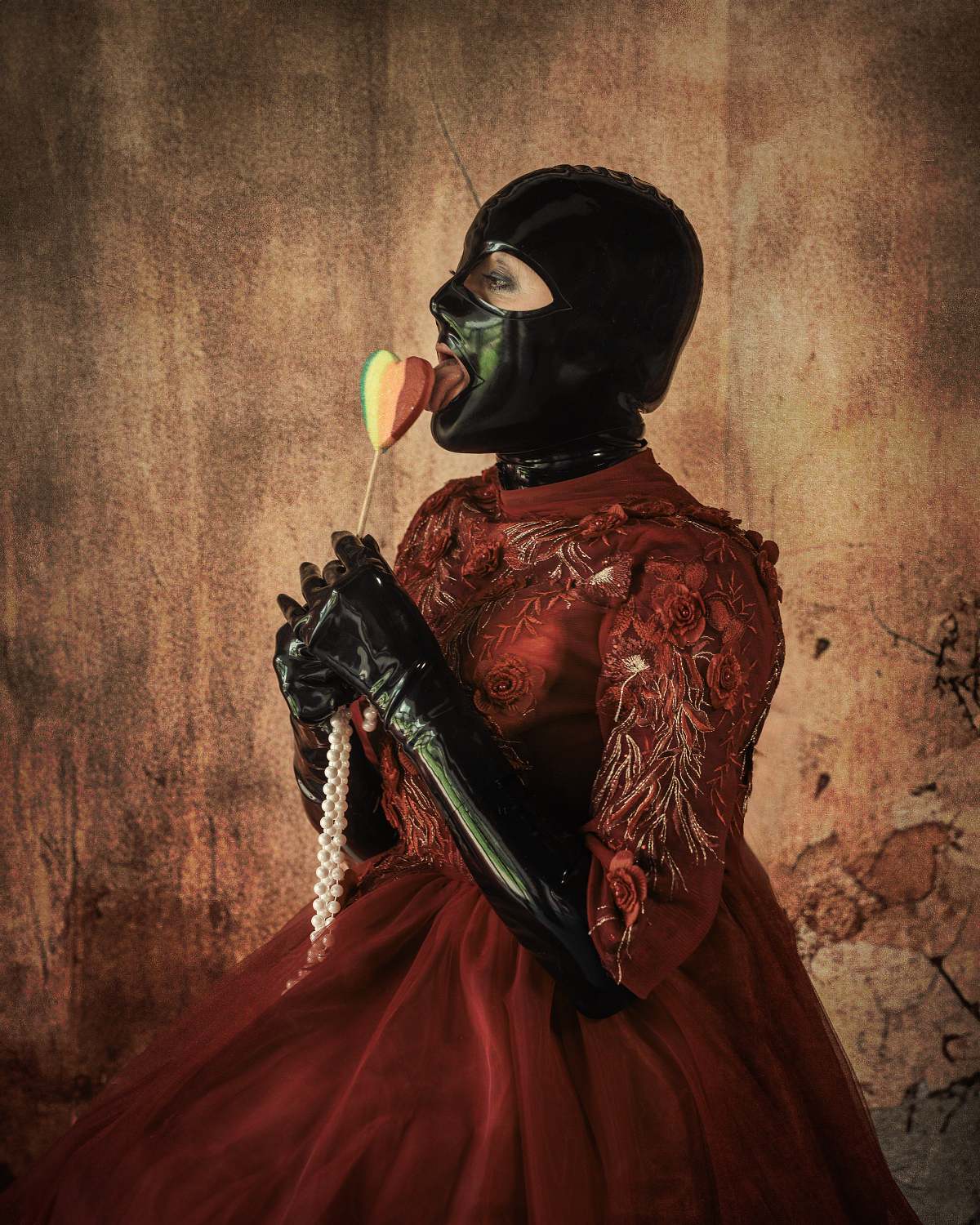 femme en robe rouge de princesse et tenue latex, l&eacute;chant une sucette, regard provocateur, ambiance d&eacute;cal&eacute;e et baroque, photographie fine art