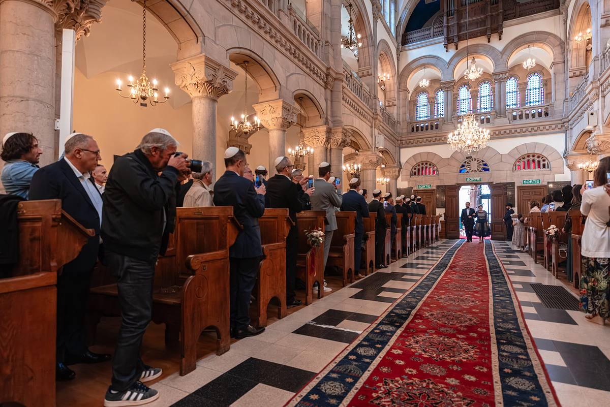 Invit&eacute;s r&eacute;unis dans la synagogue pendant l'entr&eacute;e du mari&eacute;e et sa maman &agrave; la c&eacute;r&eacute;monie de mariage