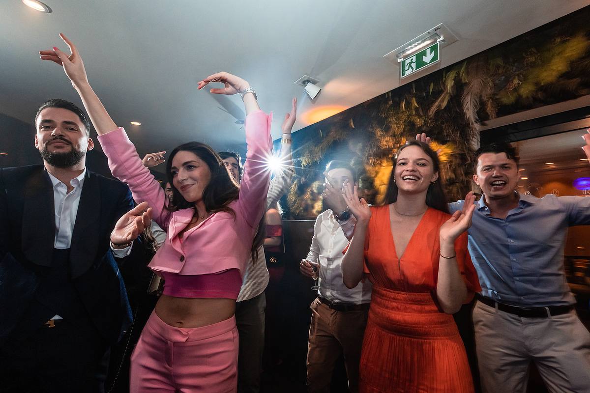 L'&eacute;nergie de la f&ecirc;te bat son plein alors qu'un groupe d'invit&eacute;s ex&eacute;cute des pas de danse synchronis&eacute;s, exprimant leur joie dans une salle &eacute;l&eacute;gamment &eacute;clair&eacute;e, une sc&egrave;ne capt&eacute;e par Sebastien CLAVEL Photographe mariage Lyon
