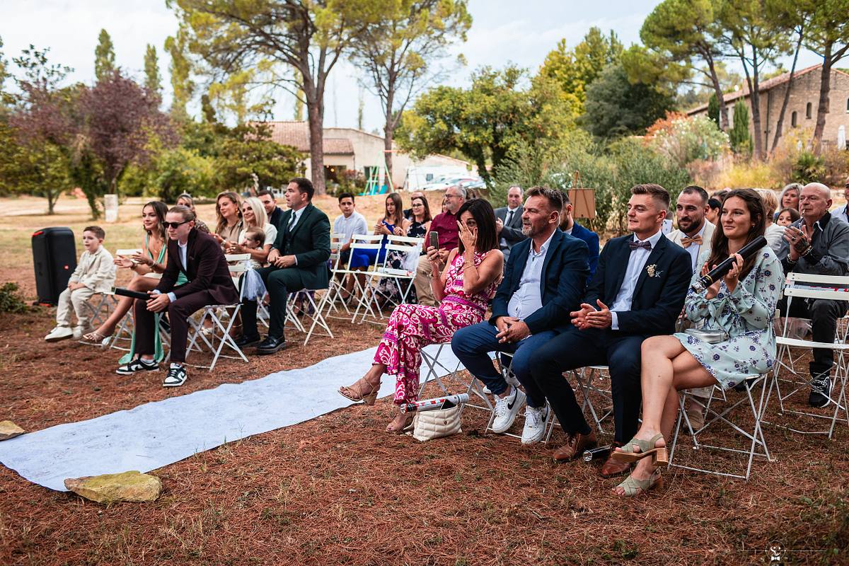 Vue des invit&eacute;s souriants et applaudissant lors d'une c&eacute;r&eacute;monie de mariage &agrave; N&icirc;mes, soulignant l'atmosph&egrave;re festive et chaleureuse