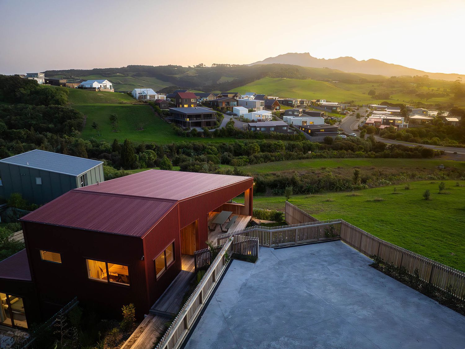 High-angle architectural drone photography of a modern residential property on the Rangitahi Peninsula in Raglan, captured at sunset by Flax Cove Studio.