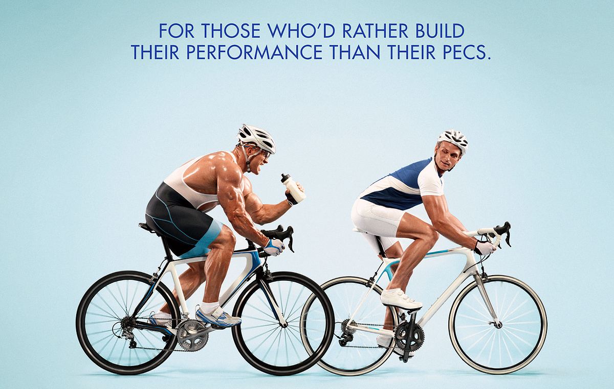 A studio shoot of two men on bikes. One fit and trim, one bulky with too much muscle.