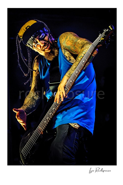 Vertical color image of Korn bassist Fieldy performing live on stage with a bass guitar in a dramatic close portrait
