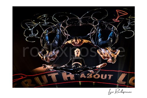 Horizontal color image of Pink performing onstage with aerial acrobats and glowing martini glass props above her