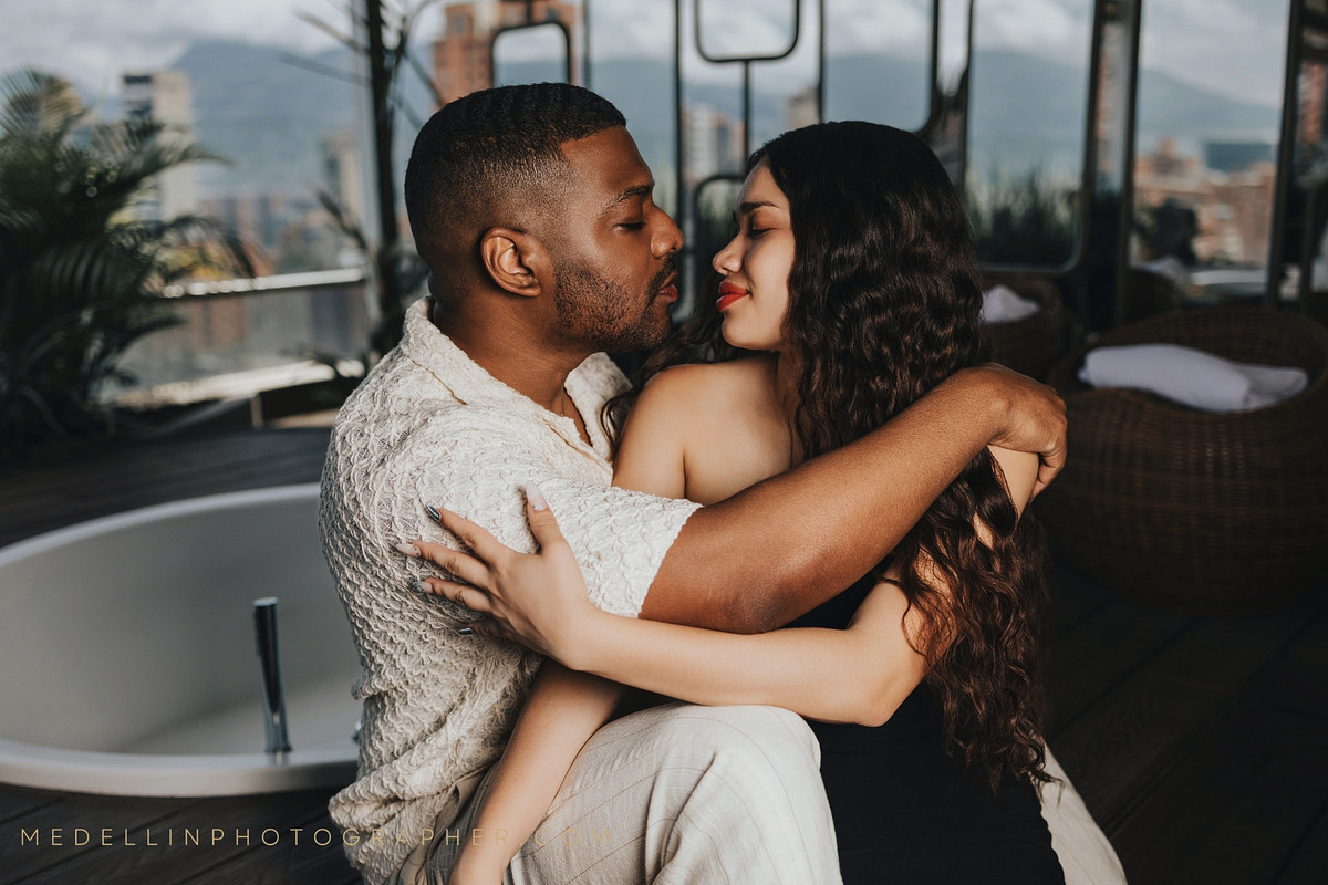 Couple embracing on a covered balcony with the Medellin mountains behind them