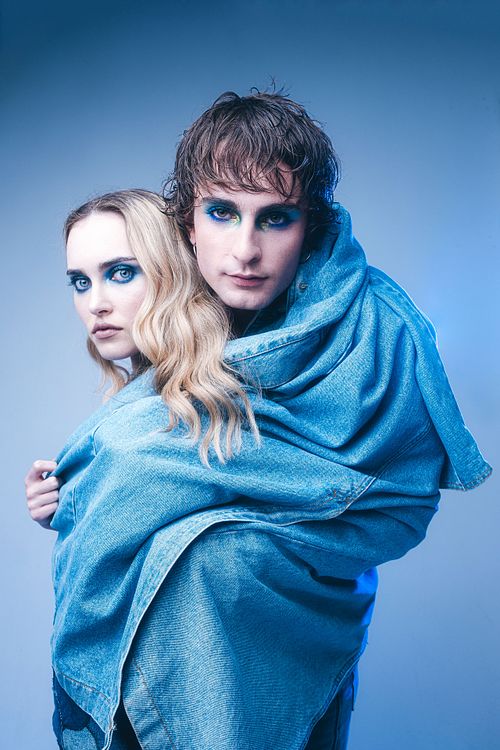 Fashion editorial scene with two models sharing a garment, creative composition, studio and location work by Mila Filippone.