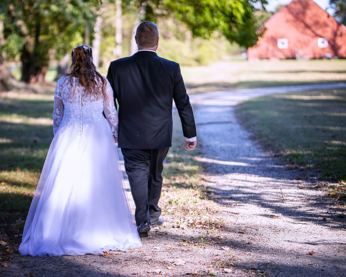 bride and groom walking towards the remodeled buildings at  ross mansion holding hands