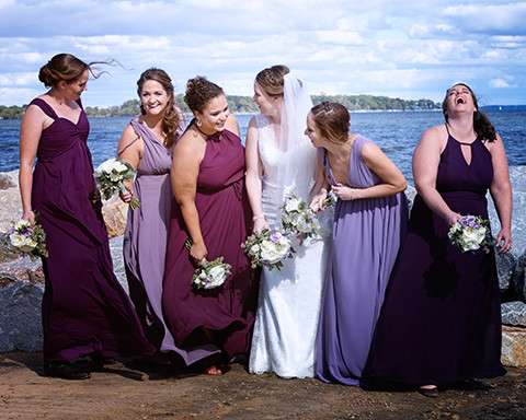 bride and her bridesmaids are laughing and being silly with the bay in the background by windsweptphotodesign
