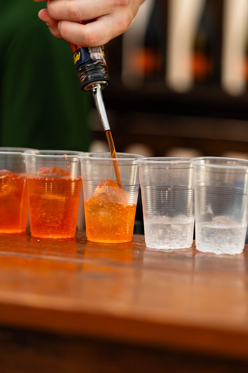 Barman nalewa pomarańczowe drinki do kubków