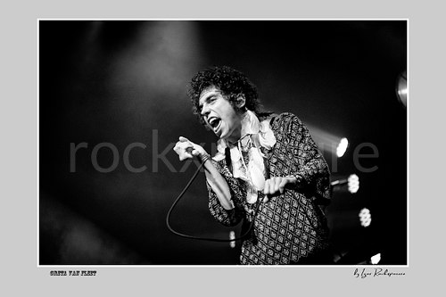 Horizontal black and white image of Greta Van Fleet singer Josh Kiszka holding a microphone during a live performance