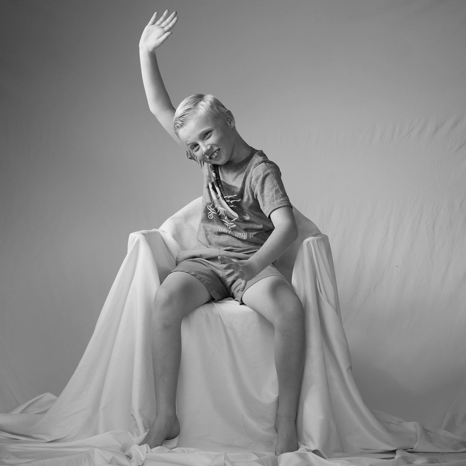 A child raising one hand in an expressive black-and-white studio portrait