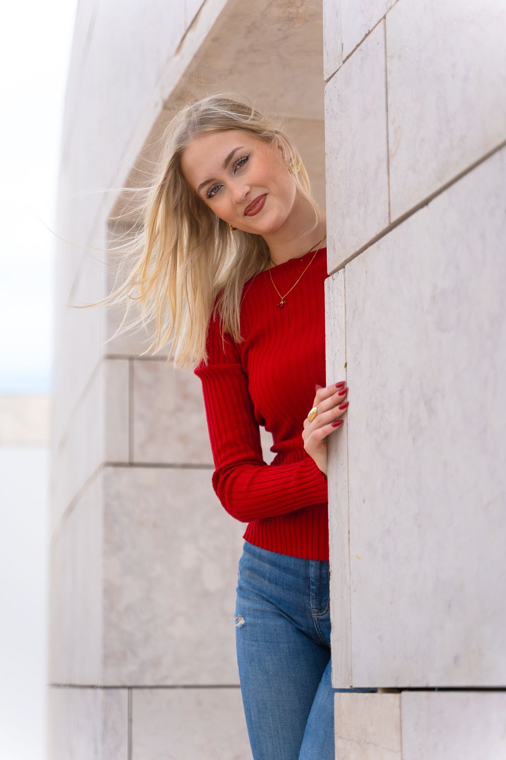 Woman in a red sweater beside a Lisbon building