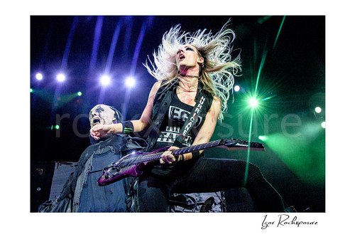 Horizontal color image of Nita Strauss performing live on stage with an electric guitar and dramatic flying hair