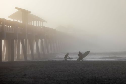 Surfers In Morning Fog Near Pier