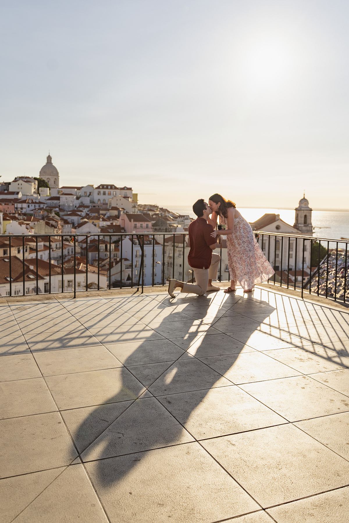 Couple sharing a kiss during a sunset proposal overlooking Alfama