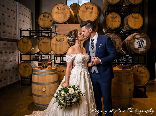 Bride and groom sharing a romantic kiss inside St. Augustine Distillery surrounded by whiskey barrels, photographed by Legacy of Love Photography.