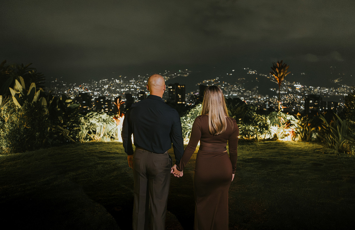 Couple watching the Medellin city lights from a hillside at night