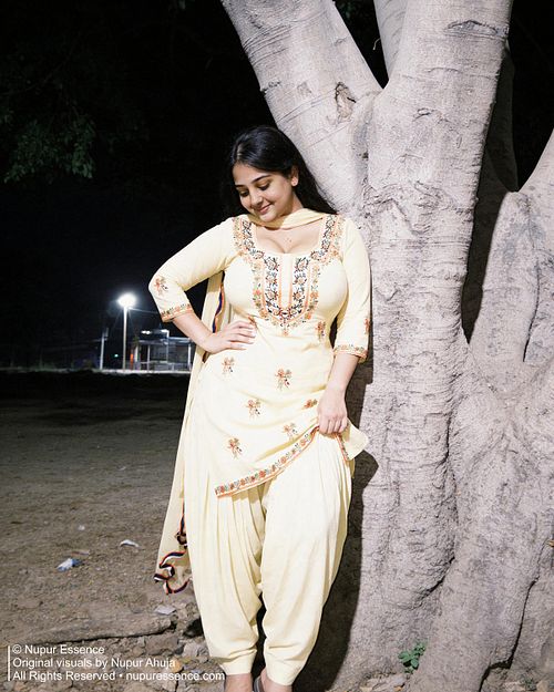 Night fashion portrait featuring Nupur Ahuja in a yellow Punjabi suit beside a tree under street lighting