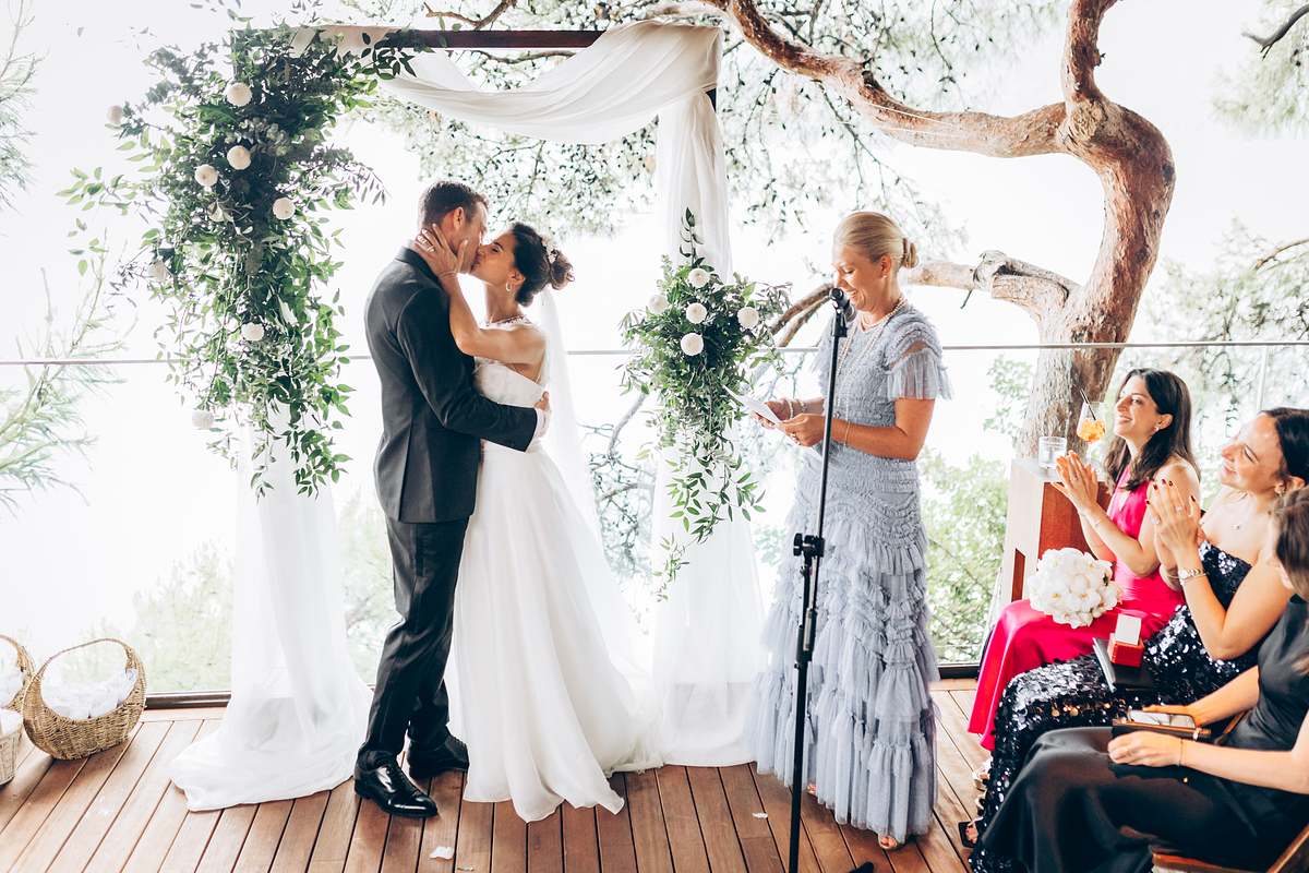 Newlyweds kissing beneath the floral arch at D-Resort Göcek
