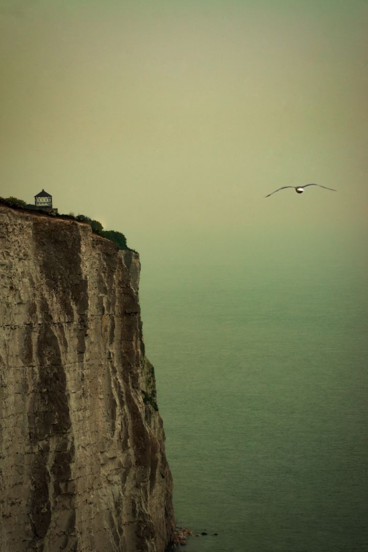 The cliffs at Beachy Head with Belle Tout Lighthouse standing above the sea, photographed in soft, misty light.