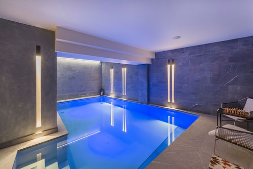 Piscine intérieure illuminée en bleu avec murs en pierre bleue dans un appartement haussmannien sur les Champs-Élysées, Paris. Photographie d’architecture intérieure par Nicolas Karadimos.