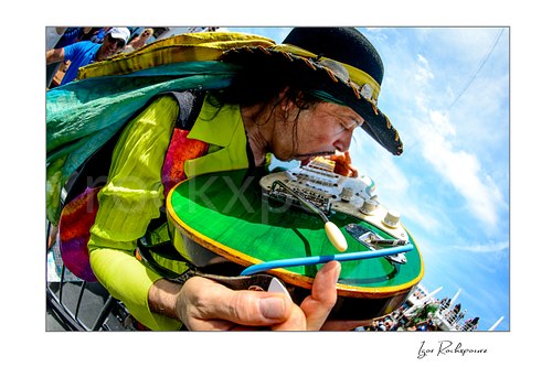 Horizontal color image of Randy Hansen in a tight outdoor ship deck close-up with a green guitar and vivid stagewear