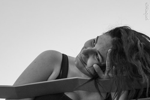 Portrait en noir et blanc d’une jeune femme posant la tête sur son bras.