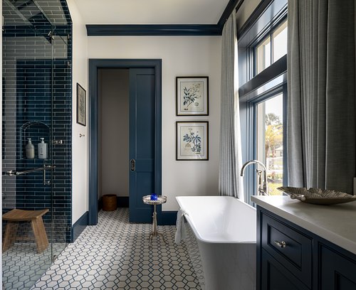 Luxury bathroom with a navy blue tiled shower, freestanding tub, and high-contrast white tile work.
