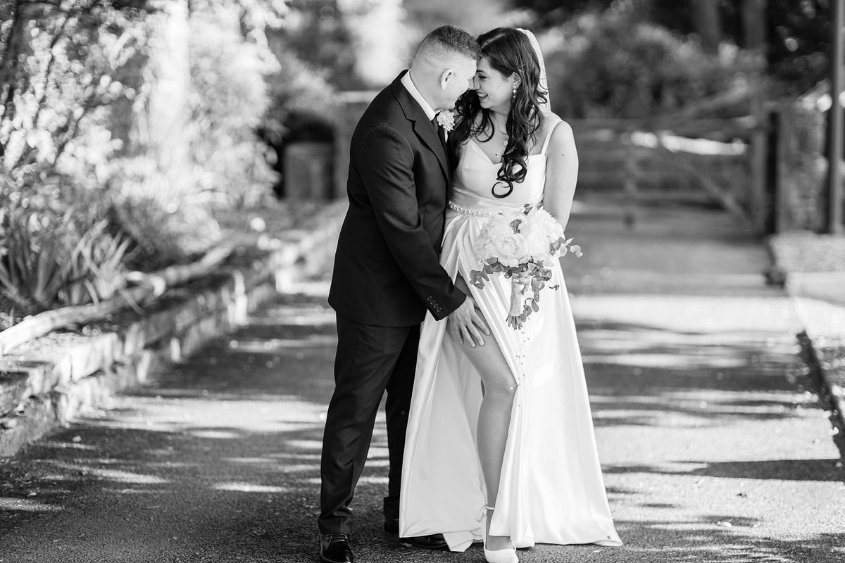 Black and white full-length portrait of bride and groom standing together outdoors in South Wales