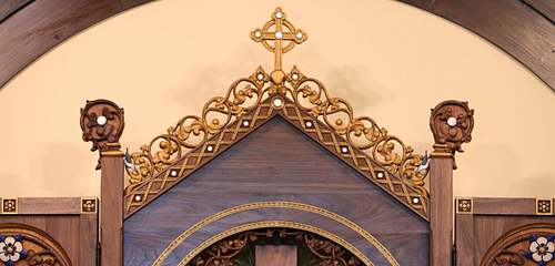 Detail photo of the upper part of the altarpiece showing the crockets, finials, cross, flowers, and nuthatches