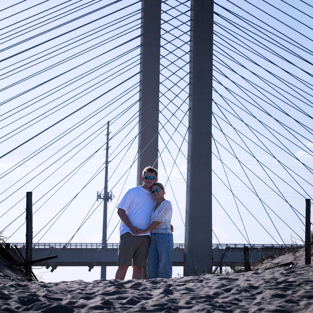 Candid, unposed wedding photo near the Indian River Inlet bridge, showcasing authentic interactions and coastal textures.