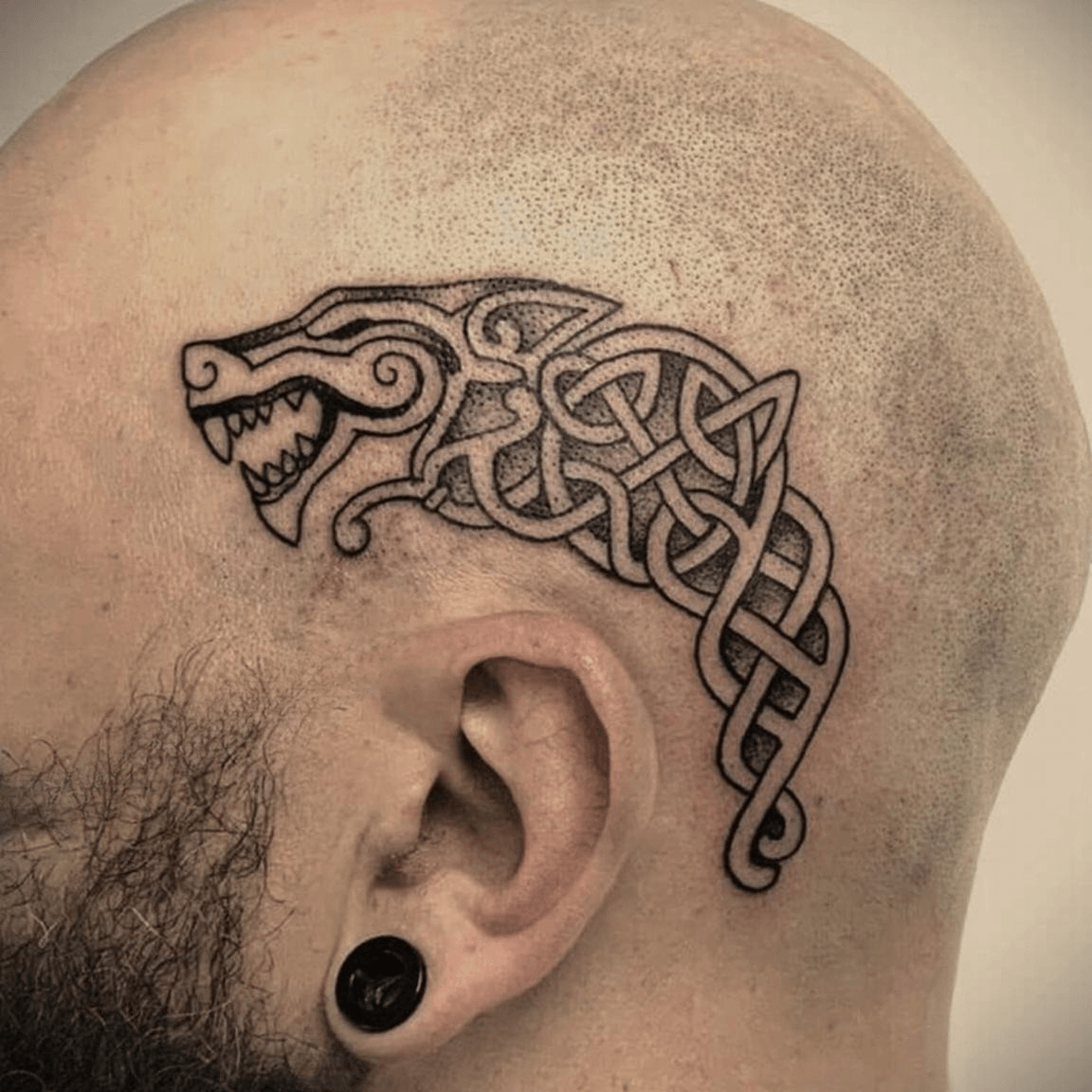 Fine line Viking inspired tattoo featuring a warrior head, wolf motif, and Celtic knotwork details, clean black ink linework created in Stoke-on-Trent by Alika Tattoo Art.