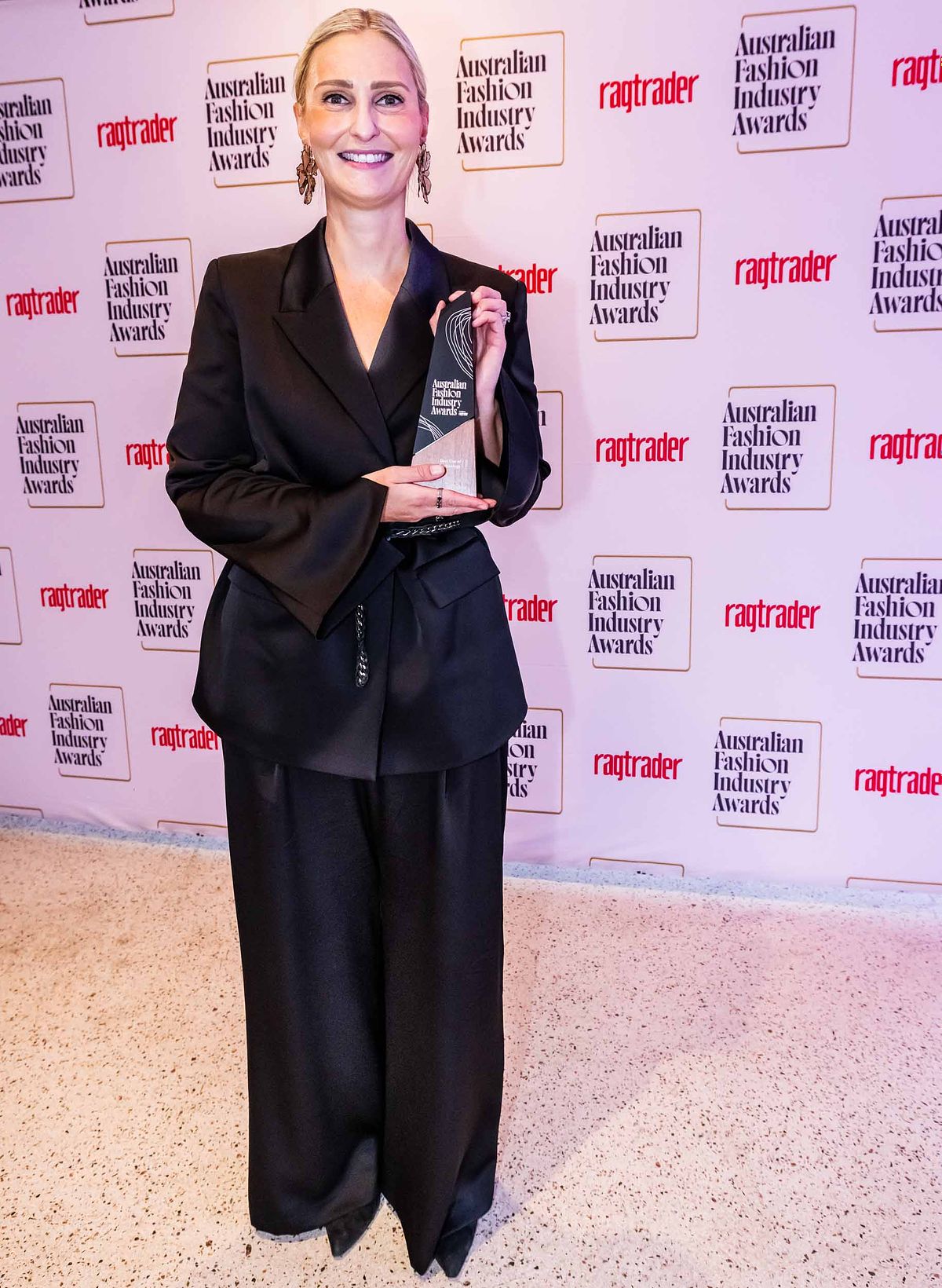 A female award winner poses with her trophy at the Yaffa Media &ndash; Ragtrader, Australian Fashion Industry Awards.