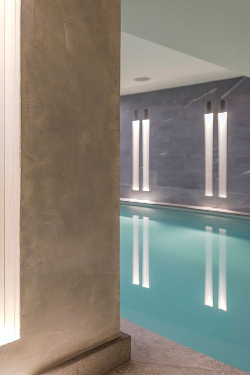Piscine intérieure avec éclairage vertical et murs en béton dans un appartement haussmannien sur les Champs-Élysées, Paris. Photographie d’architecture intérieure par Nicolas Karadimos.