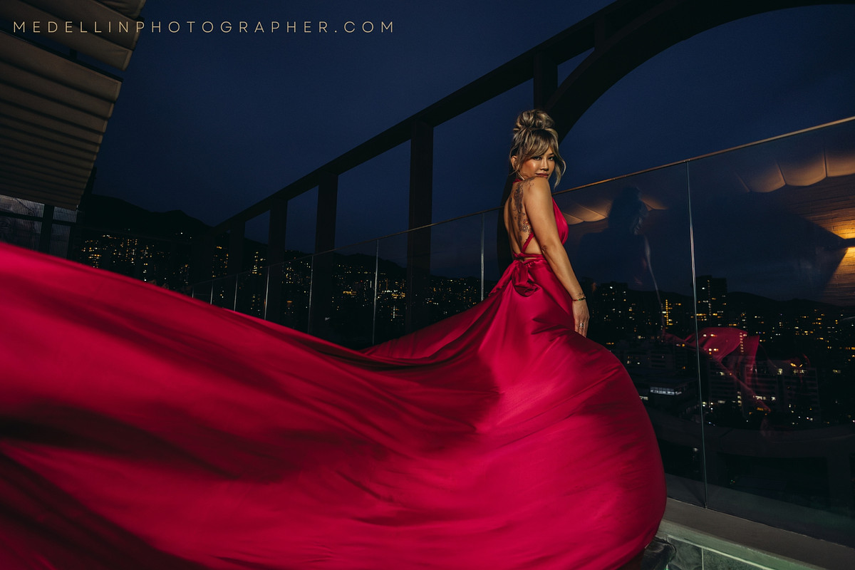Woman in a flowing red dress on a Medellin rooftop at blue hour