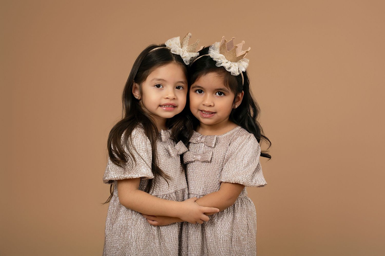 Sibling portrait session in a professional studio with controlled lighting, featuring two children smiling together.