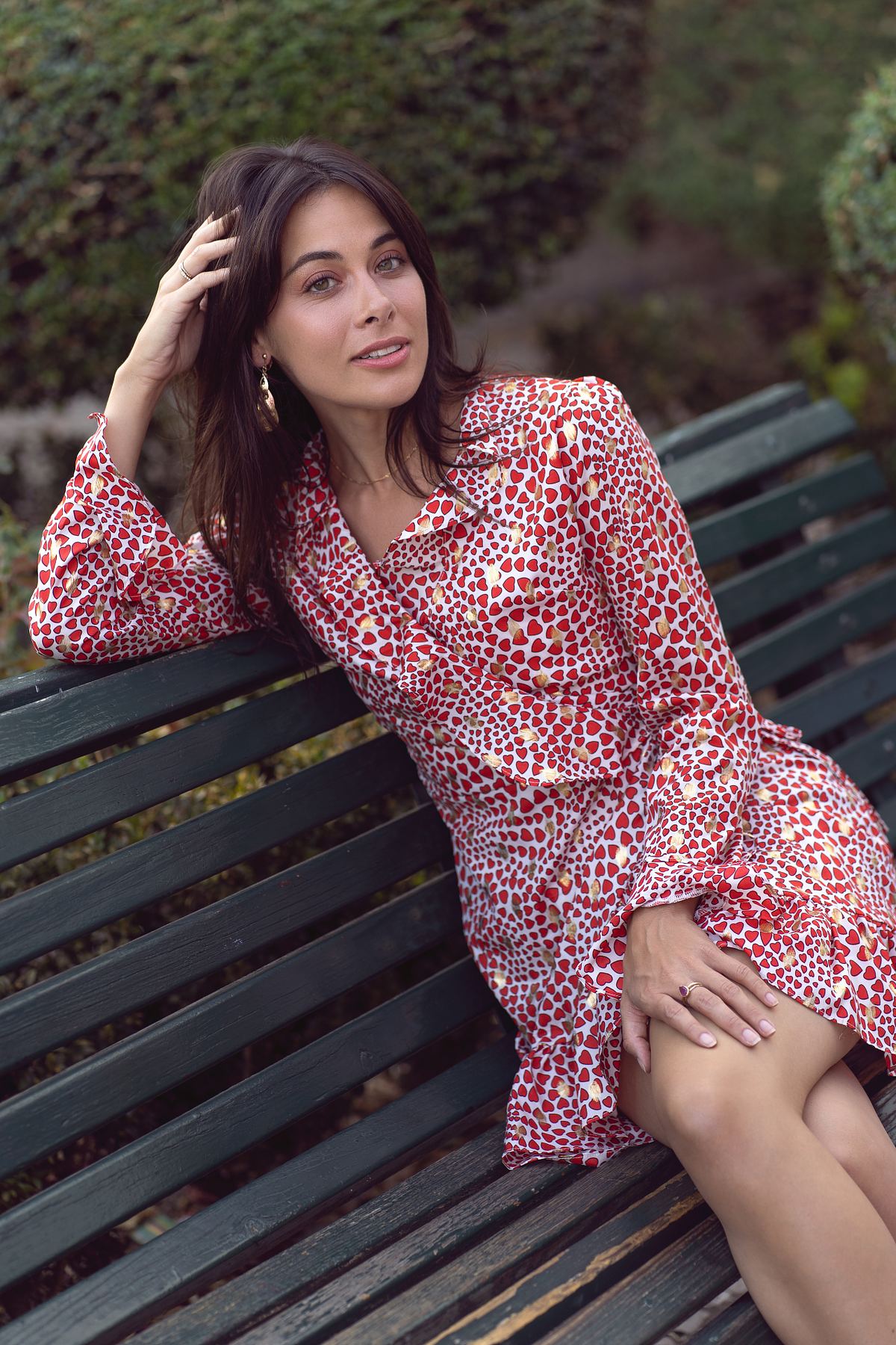 Woman in a red dress posing on a park bench