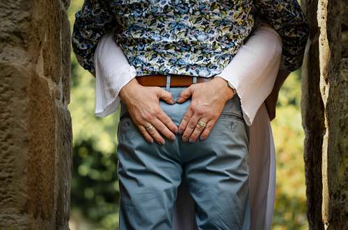 Detailaufnahme des Bräutigams in gemustertem Hemd und Jeans, Hände vor dem Körper