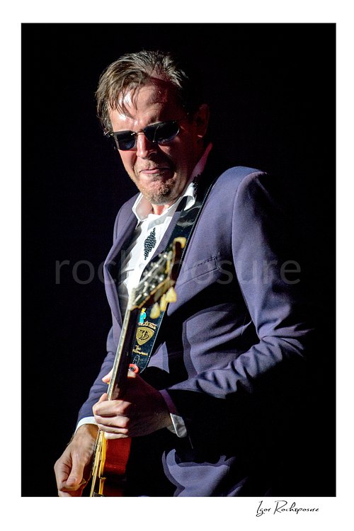Vertical color image of Joe Bonamassa performing live on stage with a guitar in a close concert portrait